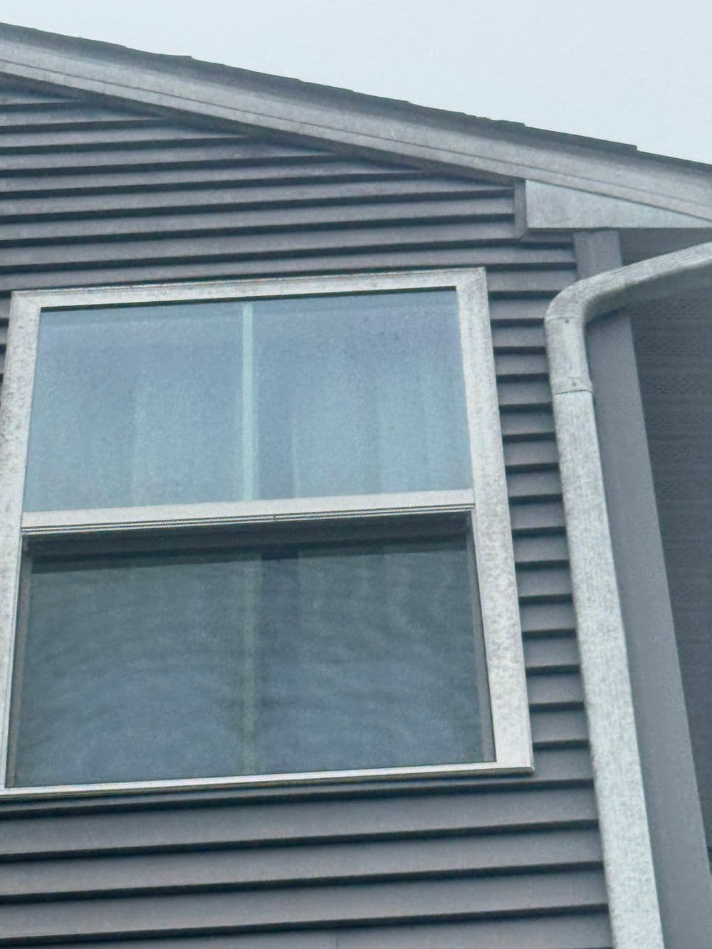 Close-up of a window on a modern gray house with textured siding.