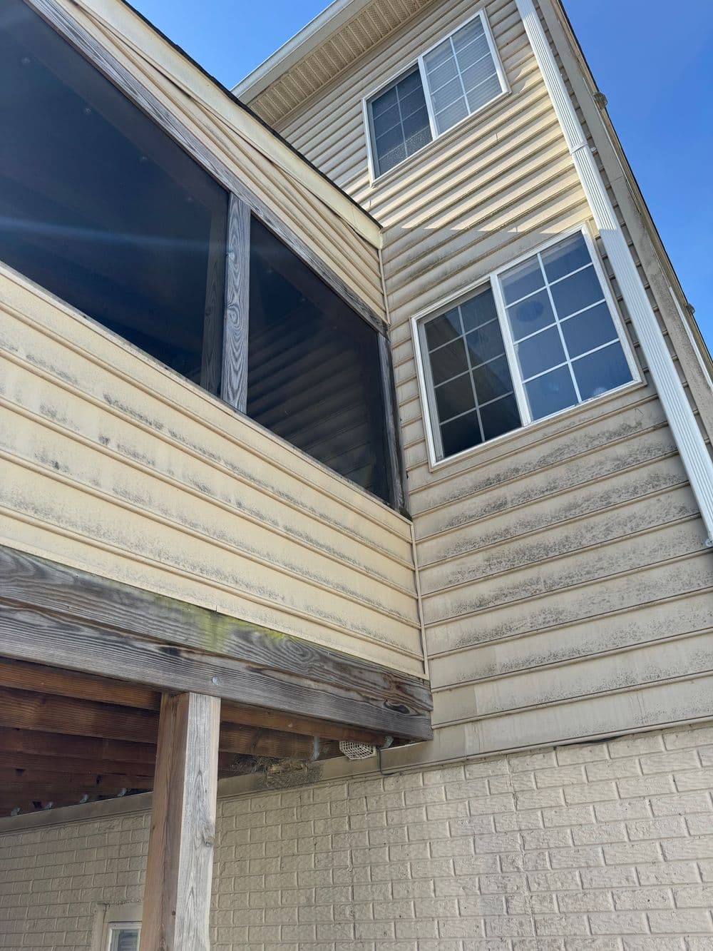 View of a multi-story building featuring a screened porch and large windows against a blue sky.