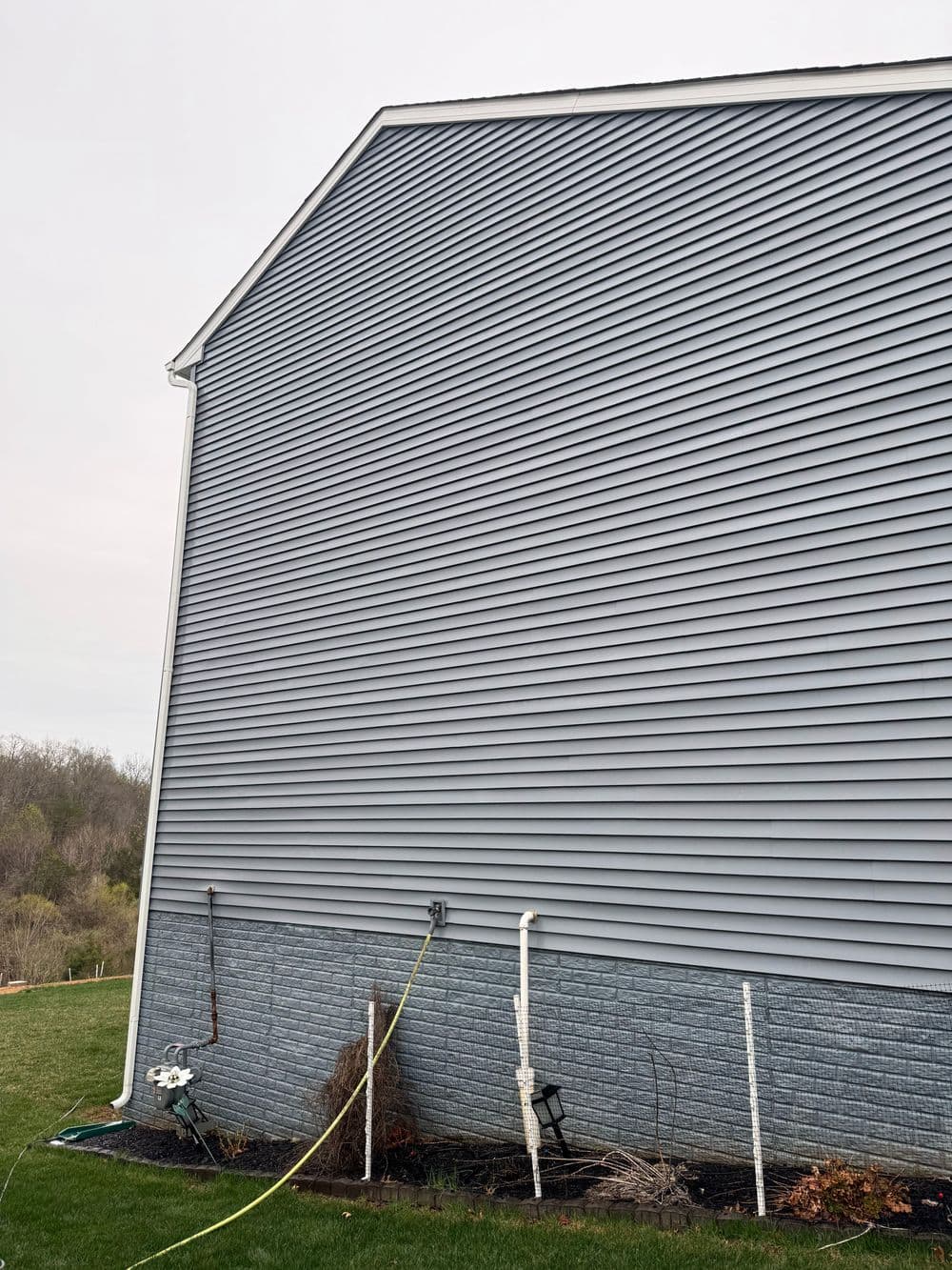 Side elevation of a house featuring gray vinyl siding and landscaping details.